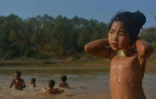 Une fillette Kayan porte des anneaux de bronze autour du cou - signe de beauté dans sa tribu - alors que d'autres enfants se baignent dans le lac, à Panpet, près de Demoso, dans l'Etat Kayah, au centre de la Birmanie, le 6 mars 2016