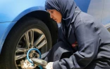 Une femme ajustant le plneu d'une voiture dans un garage à Jeddah, en Arabie saoudite, le 26 mai 2022