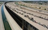 Vue aérienne de migrants attendant le long du mur frontalier pour se rendre aux agents américains des douanes et de la protection des frontières après avoir traversé le fleuve Rio Grande vers les États-Unis, le 11 mai 2023 à El Paso, au Texas