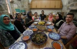 Des Palestiniennes et des étrangers assis à table devant des spécialités palestiniennes préparées lors d'un cours de cuisine à la maison de Fatima Kadumy (3e g), le 19 septembre 2015 à Naplouse
