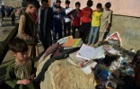 Des gens regardent des sacs d'élèves et des livres scolaires le 9 mai 2021 sur les lieux d'un attentat qui a frappé une école de filles près de Kaboul la veille