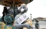 Un militant pose des masques le 31 mars 2018 devant la bouche de statues place de la Concorde, afin de dénoncer l'inaction des pouvoirs publics contre la pollution de l'air