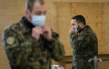 Deux militaires de l'armée suisse enfilent un masque de protection lors d'une formation à Bière (ouest) le 22 mars 2020