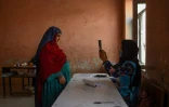 Une responsable de bureau de vote scanne avec un appareil biométrique une électrice, à Mazar-i-Shraif en Afghanistan, le 28 septembre 2019 pour l'élection présidentielle