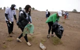 Des bénévoles ramassent des déchets lors d'une campagne de nettoyage de M'Hamid El Ghizlane, aux portes du désert, dans le sud Maroc, le 12 avril 2025