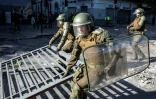 Des policiers anti-émeutes déblaient une barricade pendant des heurts avec des manifestants antigouvernementaux le 28 octobre à Santiago (Chili)