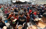 Des Palestiniens lors d'une distribution gratuite de nourriture dans le camp de réfugiés de Nuseirat, dans le centre de la bande de Gaza, le 12 avril 2025