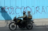 Les policiers de la Garde nationale passent devant un graffiti disant que le Venezuela bascule sous une dictature, le 6 juillet 2017 à Caracas