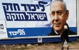 Une arabe israélienne marche devant une affiche électorale montrant le Premier ministre israélien Benjamin Netanyahu, à Haïfa (nord), le 4 avril 2019