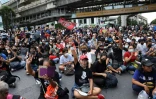 Des manifestants rassemblés à un important croisement à Bangkok font le salut à trois doigts, signe de ralliement du mouvement de protestation, le 18 novembre 2020