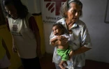 Une employée de l'organisation caritative Caritas porte un bébé Yukpa dans ses bras à la mission d'El Tucuco, le 12 juin 2019 au Venezuela