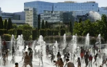 Les Parisiens se rafraichissent sous les fontaines du parc André Citroën à Paris le 5 août 2018
