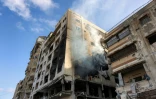 De la fumée s'échappe d'un immeuble résidentiel touché la veille par une frappe israélienne dans le quartier d'Al-Ramal à Gaza, le 16 mai 2026