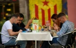 Un groupe de touristes assis devant un graffiti représentant le drapeau pro-indépendant de la Catalogne, le 13 septembre, à Barcelone. 