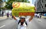 Un manifestant antigouvernemental brandit une pancarte dénonçant la "dictature" du président Maduro, le 1er mai 2019 à Caracas