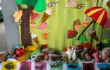 Des peluches et des jeux disposés par terre dans  "l'école du feu rouge", qui accueille des enfants défavorisés dans des conteneurs aménagés en salles de cours sous un pont autoroutier, le 18 mai 2026 à Bombay