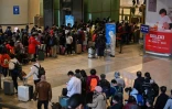 Des voyageurs font la queue pour passer au contrôle de leur température et de leur identité à leur arrivée à la gare de Wuhan, dans la province chinoise du Hubei, le 28 mars 2020