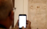 Un visiteur photographie "L'homme de Vitruve" à l'ouverture de la grande rétrospective consacrée à Léonard de Vinci au Musée du Louvre, le 22 octobre 2019 à Paris