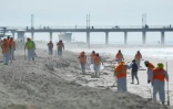 Des équipes de nettoyage dépolluent le sable près du ponton de Huntington Beach, en Californie, après une fuite sur un oléoduc voisin, le 5 octobre 2021