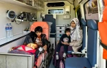 Une femme est assise avec ses enfants dans une ambulance après avoir été évacuée avec d'autres Palestiniens de la bande de Gaza au poste frontière de Rafah, dans le nord-est de l'Egypte, le 30 décembre 2023