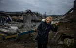 Une femme prend un peu de repos après avoir traversé un pont déruit pour quitter la ville d'Irpin, au nord-ouest de Kiev, le 7 mars 2022