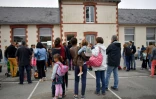 Des enfants et leurs parents devant une école primaire