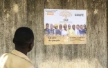 Un homme regarde une affiche électorale de la Dynamique pour la majorité du peuple (DMP), regroupement au Togo de partis politiques de l’opposition et d’organisations de la société civile, à Lomé le 24 avril 2024
