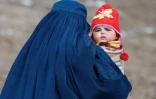 Une femme en burqa, son enfant dans les bras, se rend à un poste de santé du village d'Aab Bareek du district d'Argo, dans la province de Badakhshan, le 26 février 2024 en Afghanistan