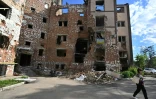 Une femme passe le long d'un immeuble détruit à Irpin, dans la région de Kiev, le 3 juin 2022
