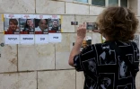 Une femme photographie les portraits des quatre otages libérés par l'armée israélienne lors d'une opération, le 8 juin 2024 à Tel-Aviv
