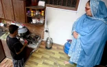 Farzana Augustine (d) et son mari Augustine Saddique qui prépare le thé dans leur cuisine à Karachi, le 18 août 2024 au Pakistan