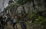 Un homme porte une fenêtre arrachée d'une maison lors de sa démolition à Kinshasa, après que les autorités de la RDC ont décidé de démolir tous les bâtiments non autorisés dans les zones inondables, le 8 mai 2025 en RDC