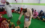 Un enseignant distribue des copies du Coran dans une madrasa pour les personnes transgenres, à Dacca le 6 novembre 2020