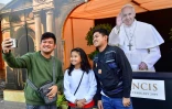 Des fidèles catholiques prennent un selfie à côté d'une photographie du pape François, devant l'église Sainte Marie à Dubaï, aux Emirats arabes unis, le 30 janvier 2019   