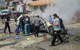 Des secouristes et des passants éteignent un véhicule en feu, cible d'une frappe de drone israélien, dans la ville de Jiyeh, au sud de Beyrouth, le 13 mai 2026 au Liban