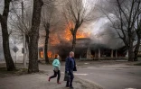 Des habitants courent dans une rue  de Seveodonetsk après un bombardement russe qui a touché une maison en flammes, le 6 avril 2022 dans la région du Donbass, dans l'est de l'Ukraine