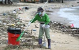 Un ouvrier nettoie la plage de Silver Mine après le passage du super typhon Ragasa près de Hong Kong, le 25 septembre 2025