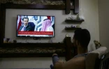 Un habitant de Damas regarde à la télévision le président syrien Bachar al-Assad reçu à Jeddah à la veille d'un sommet de la Ligue arabe, le 18 mai 2023