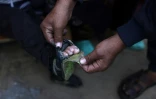 Un Palestinien montre la chaussure usée d'un enfant dans un camp de déplacés à Khan Younès, dans le sud de la bande de Gaza, le 31 décembre 2024