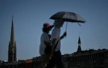 Des passants se protègent du soleil avec un parapluie à Bordeaux, le 5 juillet 2026 en Gironde, lors d'une vague de chaleur en France