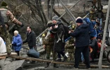 Une femme porte un chien en traversant un pont détruit à Irpin (Ukraine) pendant des bombardements, le 5 mars 2022
