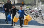 Des enfants palestiniens portent des bidons vers un camion de distribution d'eau dans un camp de personnes déplacées par la guerre à Jabalia, dans le nord de la bande de Gaza le 11 mars 2025