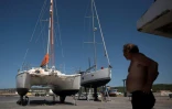 Un homme observe un catamaran attaqué par des orques alors qu'il navigue dans le détroit de Gibraltar et réparé aux chantiers navals Pecci à Barbate, dans le sud de l'Espagne, le 31 mai 2023