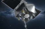 Représentation graphique de la sonde Osiris-Rex, avec le bras de collecte pointé vers le sol. Le bras va devoir déposer ses échantillons dans un container au couvercle conique au centre de la sonde (en gris sur l'image)