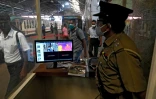 Un membre de la sécurité contrôle la température des voyageurs dans une gare de Colombo, le 26 mai 2020 au Sri Lanka