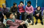 Des personnes évacuées de leurs logements en raison de l'approche d'un feu de forêt sont assises dans le gymnase de l'école élémentaire de Sinsung à Andong, en Corée du Sud, le 25 mars 2025
