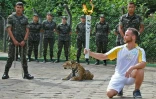 Un athlète tient la flamme olympique dans sa main près d'un jaguar, le 20 juin 2016 à Manaus (Brésil)