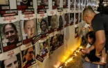 Des personnes allument des bougies sous un mur portant les portraits des otages du Hamas, lors d'une veillée demandant une action du gouvernemen pour leur retour devant le parlement israélien à Jérualem, le 7 novembre 2023