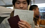 Un étudiant chinois montre son passeport et son billet de Dandong, en Chine, à Sinuiji, en Corée du Nord, à bord du train K27 en direction de Pyongyang, à la gare de Pékin, le 12 mars 2026