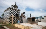 Un homme repeint une tombe dans le cimetière de Sainte-Rose-de-Lima, à Sainte-Rose en Guadeloupe, le 31 octobre 2025